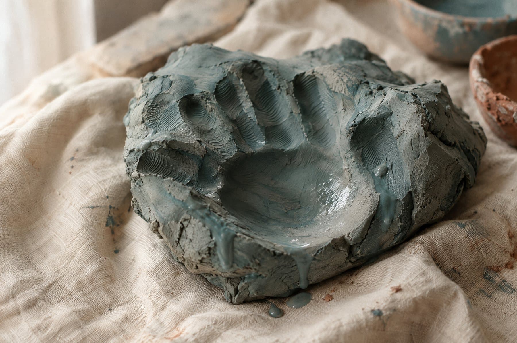 A handprint in clay, on a linen cloth